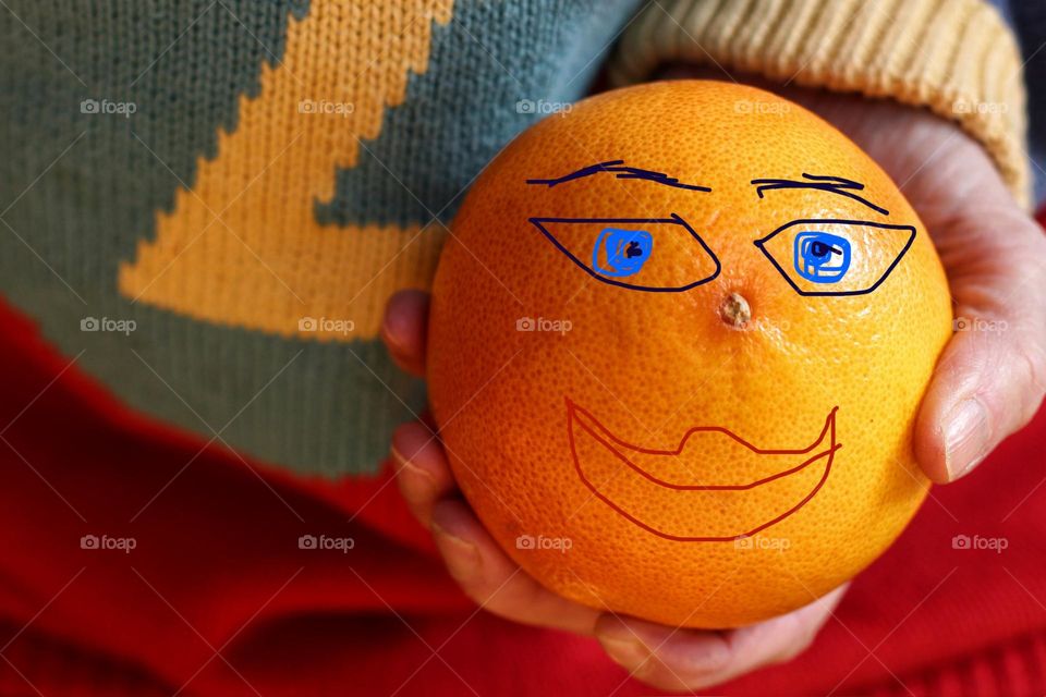 Portrait of an orange colored grapefruit with a painted face