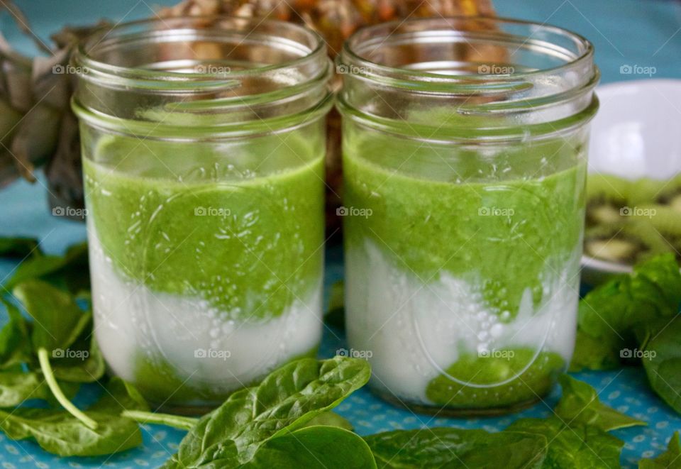 Fresh Fruit Smoothie -two spinach, kiwi, coconut milk and pineapple smoothies in pint canning jars on a turquoise tablecloth 