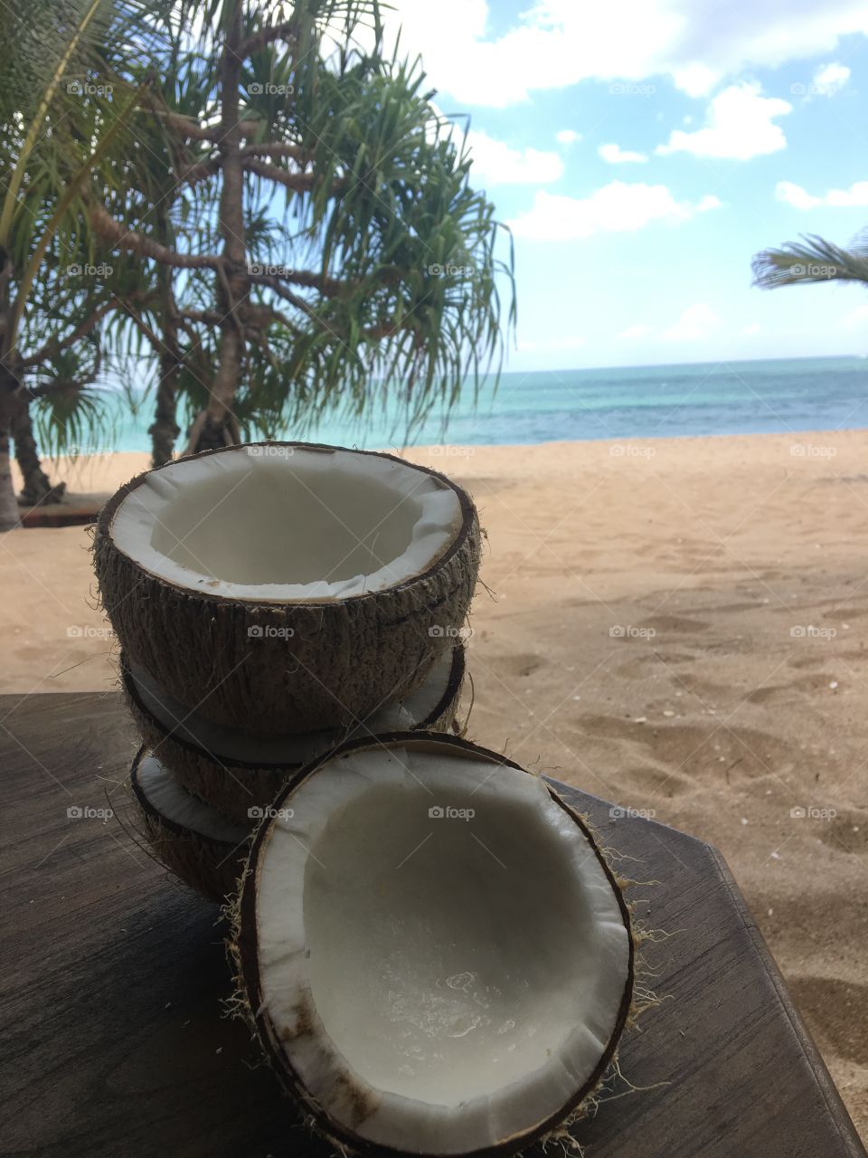 Freshly cut white coconuts by a beautiful sandy beach 