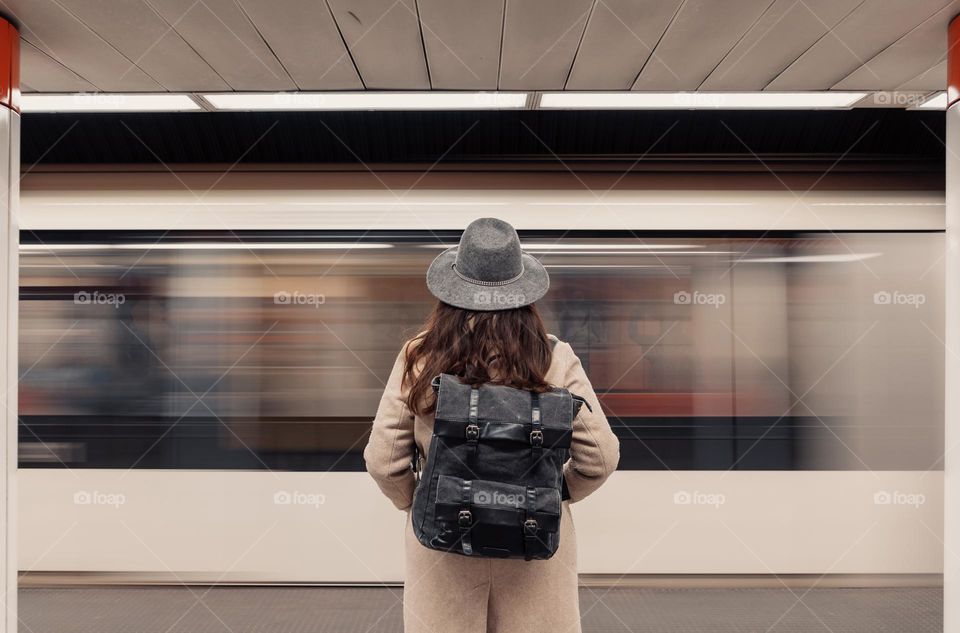 Long exposure photo of young woman standing in front of a subway train