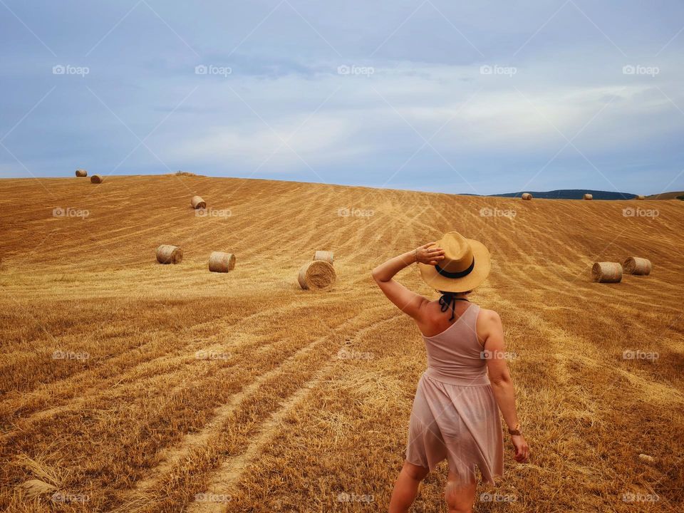 woman from behind with hat observes the vast wheat field