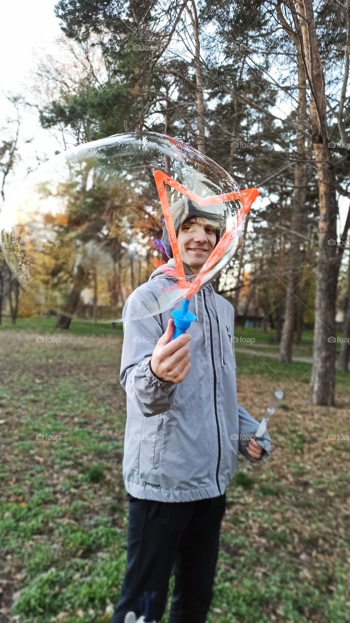 guy blowing big soap bubbles in the park