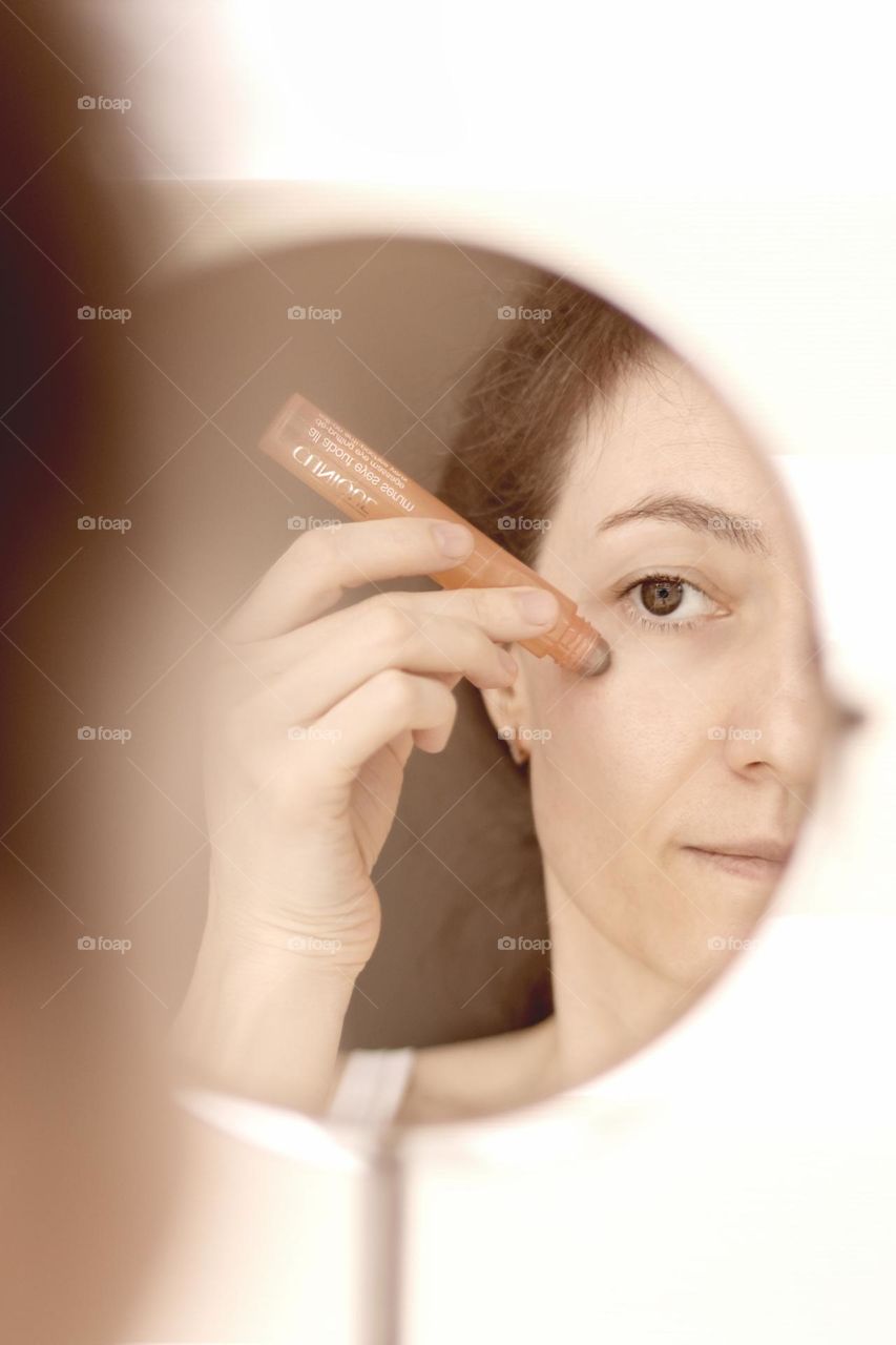 Woman using Clinique eyes serum with roll-on.