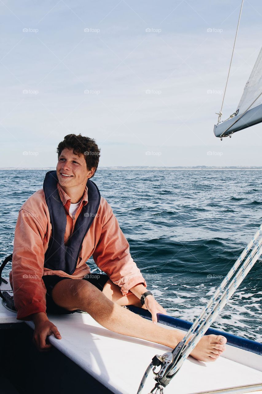 Photo of a boy with a boat in the middle of the sea