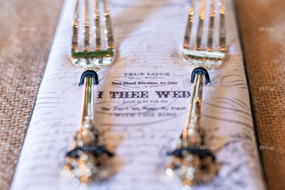 Two gold forks on text napkins on canvass table