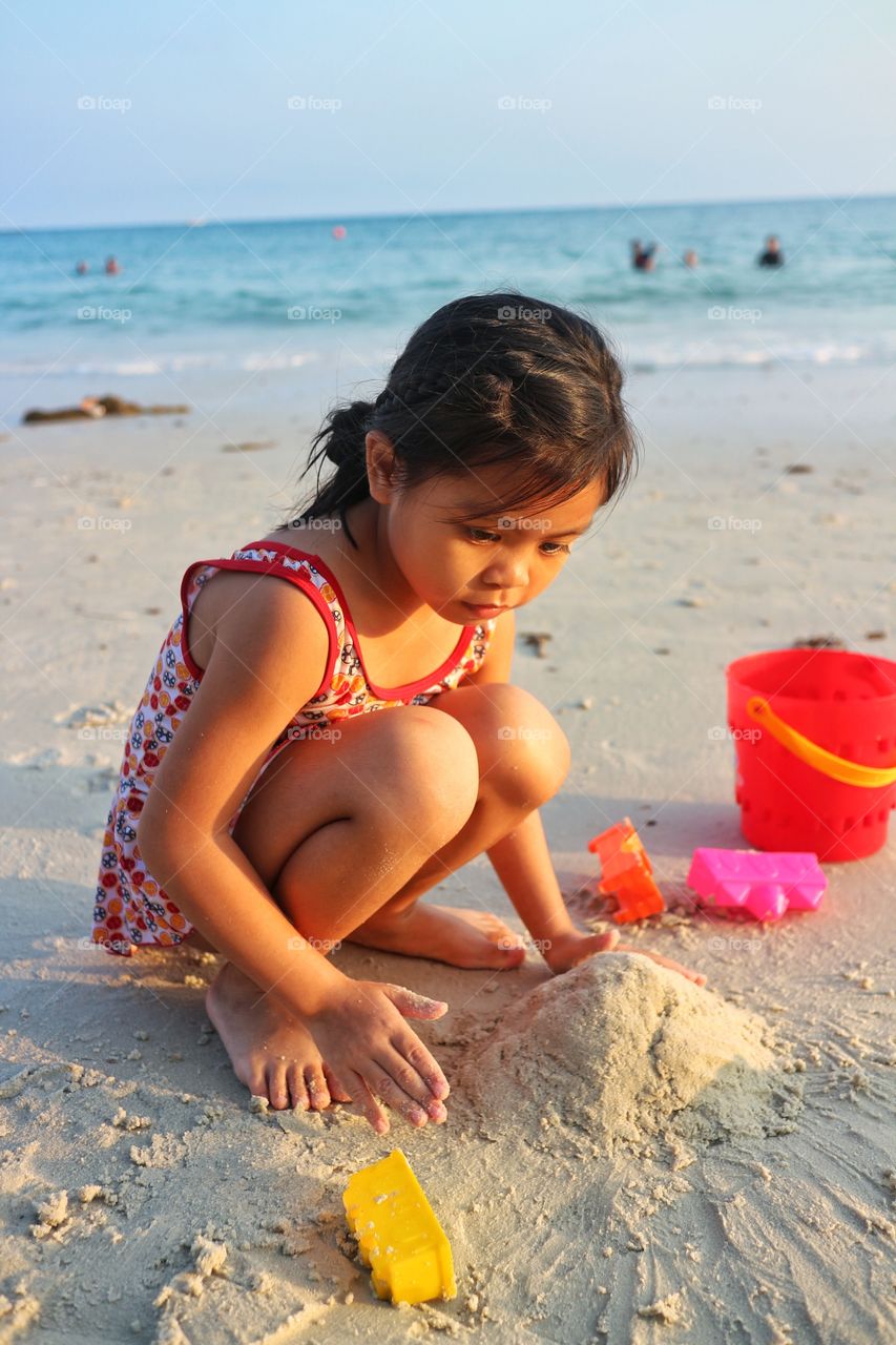 The girl playing the sand on the beach in the morning of Thailand.