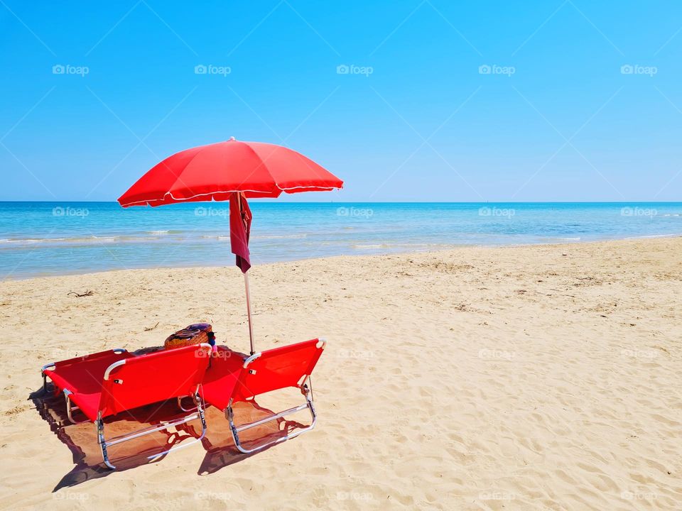 beach umbrella and red deck chairs on the deserted beach