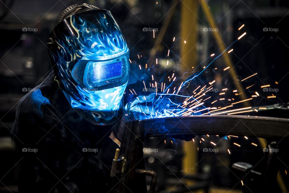 This welder is building a frame by welding bar steel together using fixtures to produce a ROPS frame for a heavy equipment Cab. 