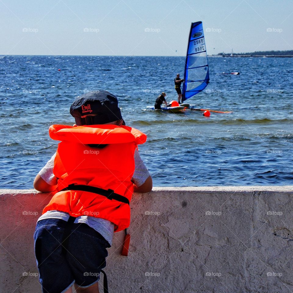 Boy watching windsurfer 