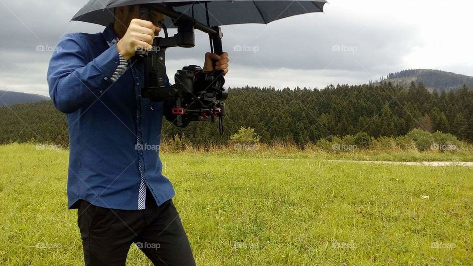 Cameraman under umbrella during rainy shooting