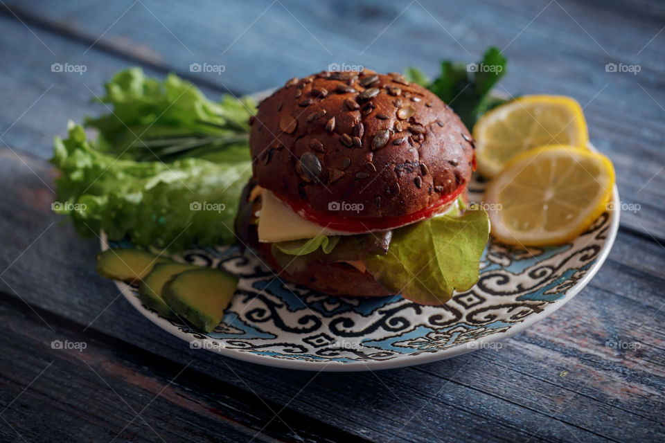 Dark burger with grain bread, cream cheese and avocado