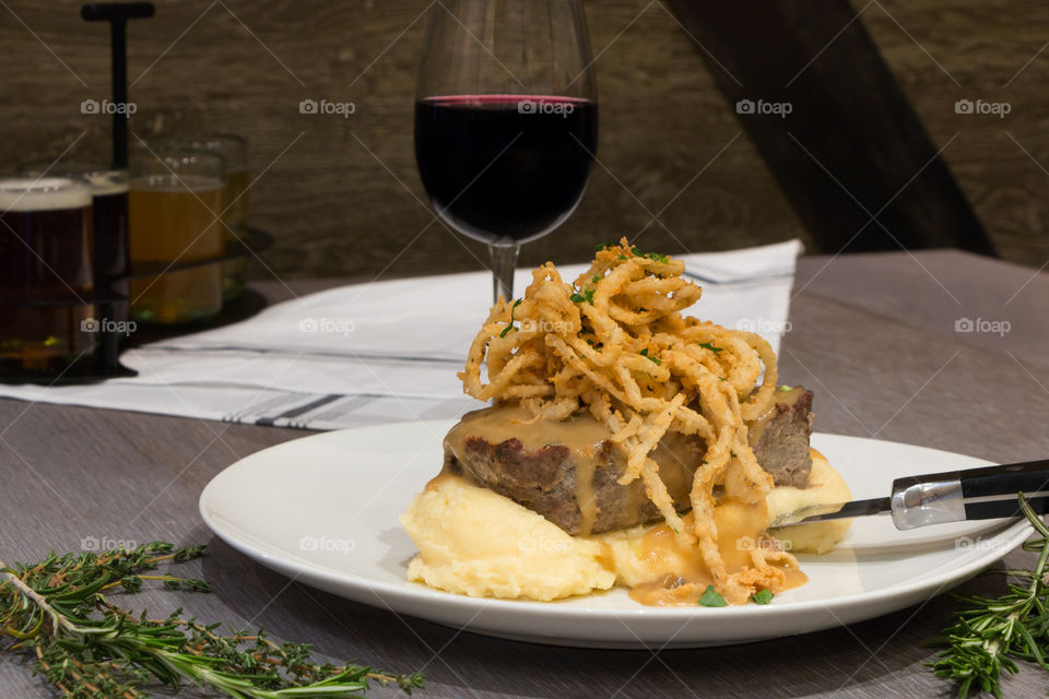 Big Meatloaf Slice Topped With Onions and Glass of Red Wine