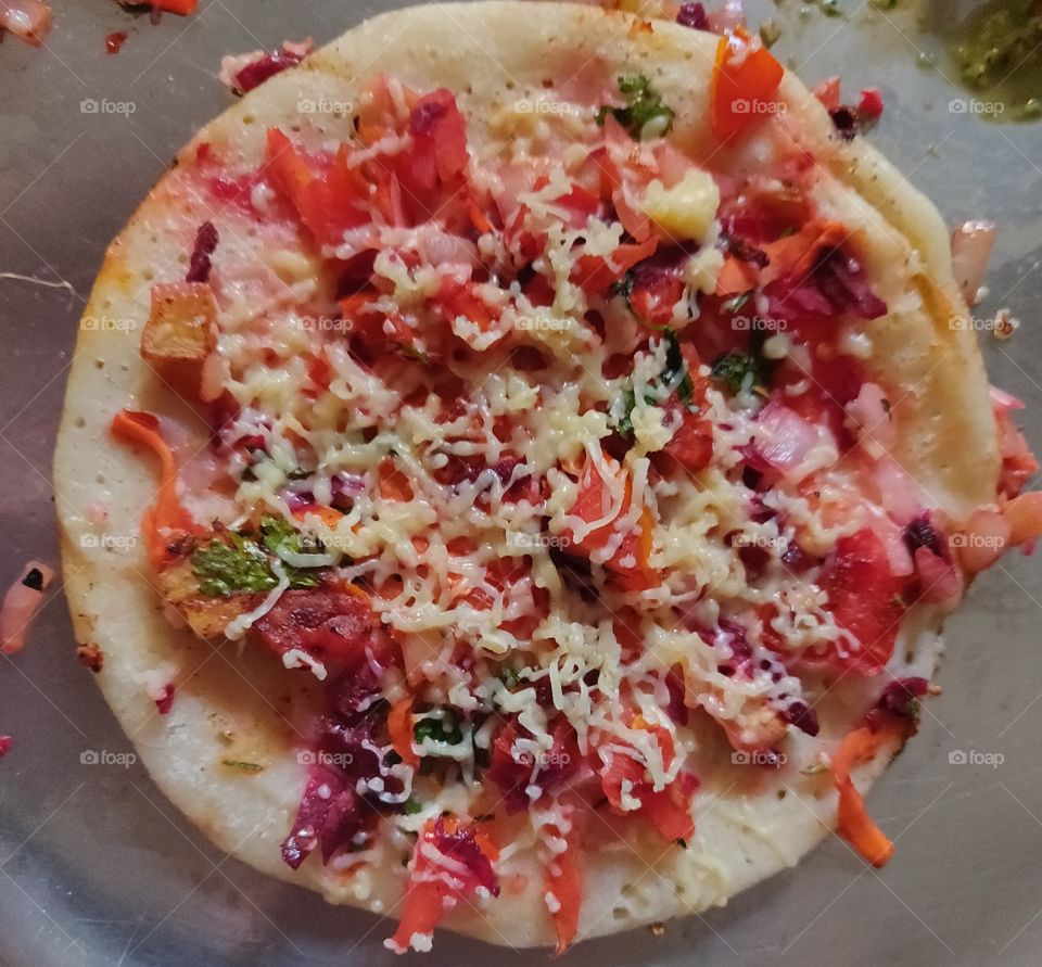 It's not a Pizza, it's an Uttapa,
Vegetables Uttapa with tomato, onion, cucumber etc, with spicy chutney /paste of coriander and green chilies.