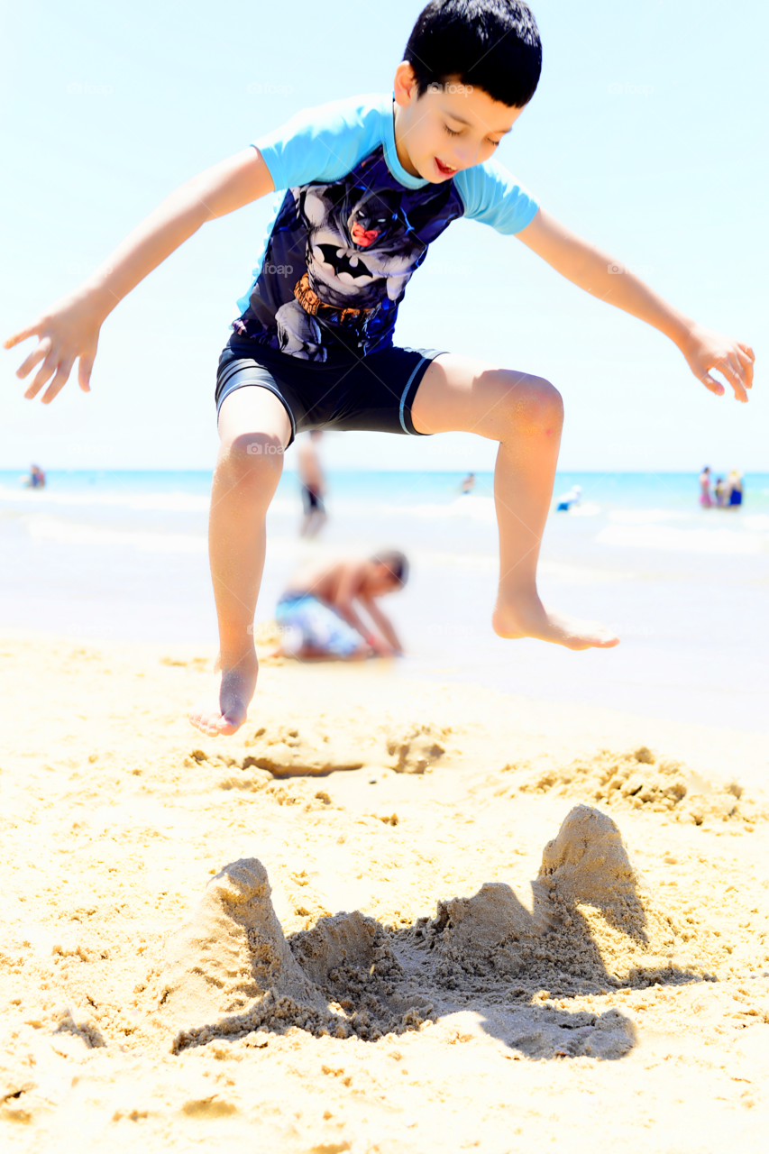 Boy jumping on sand at beach