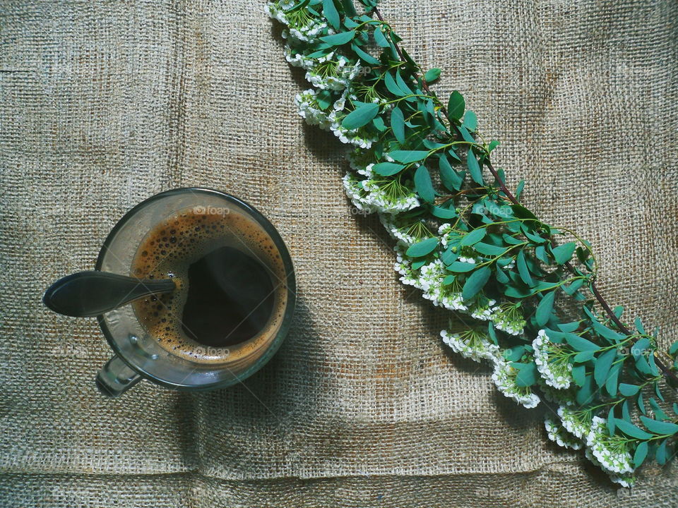 a cup of coffee and a branch with flowers