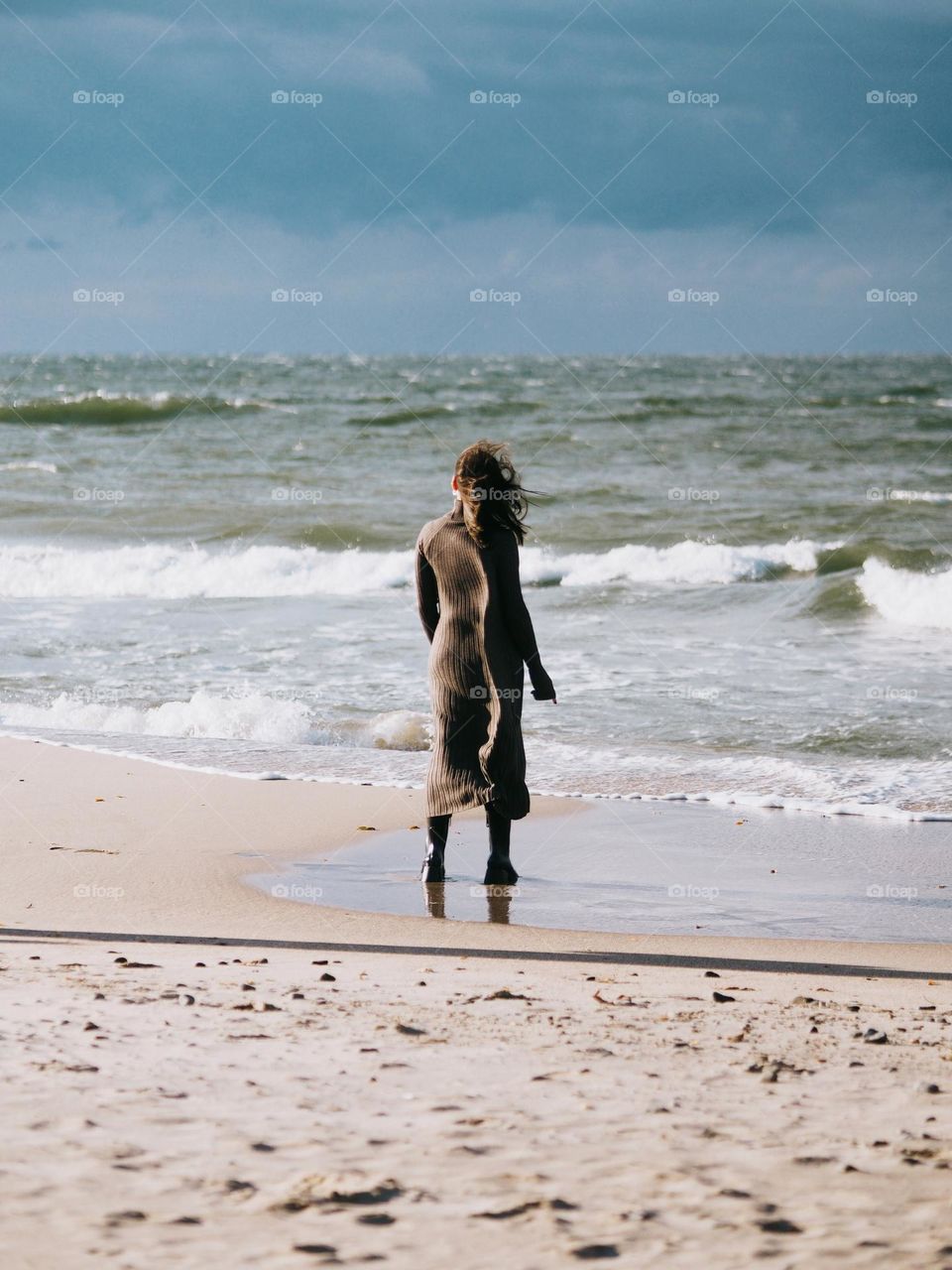 Young beautiful brunette woman standing on a seaside in sunny day, stillness 