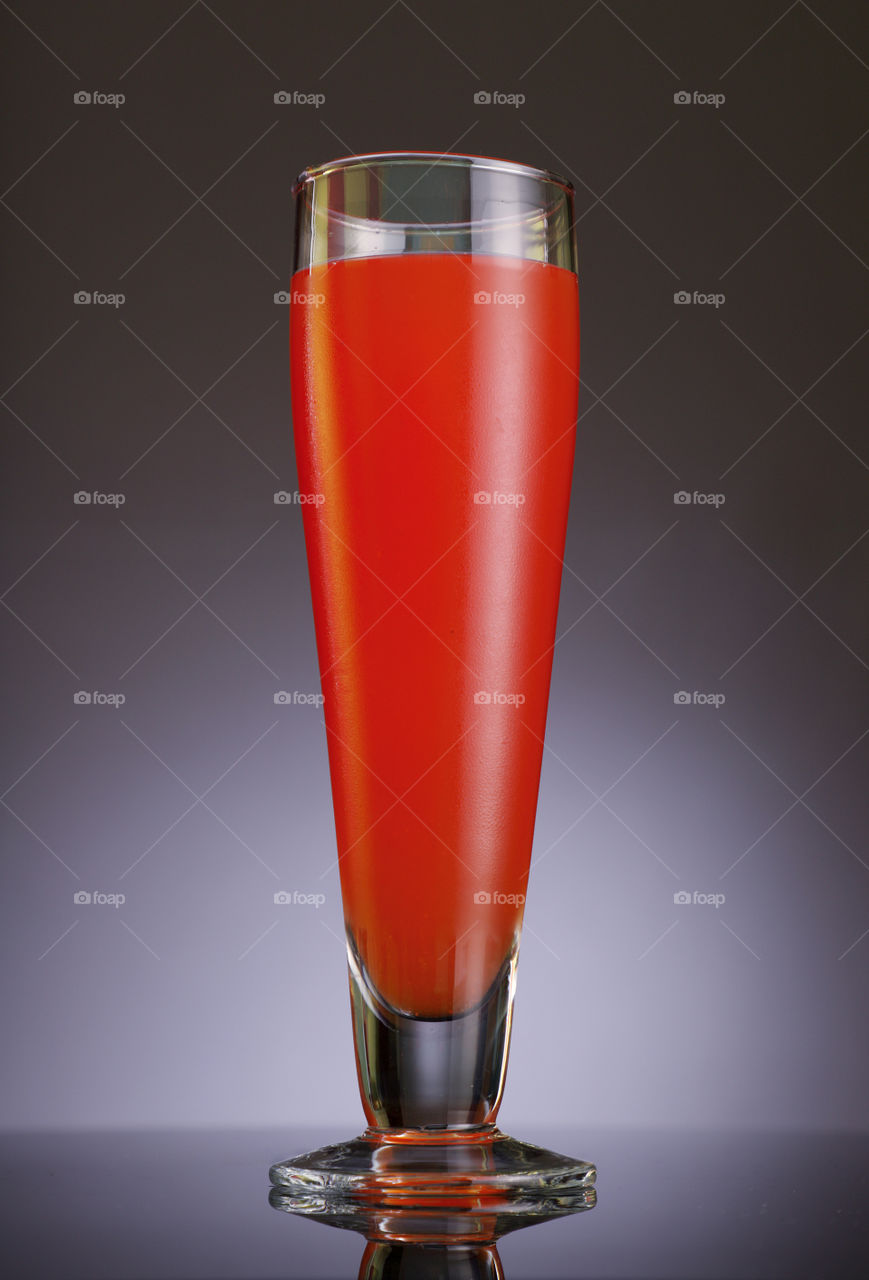Glass full of fresh and healthy juice on grey background
