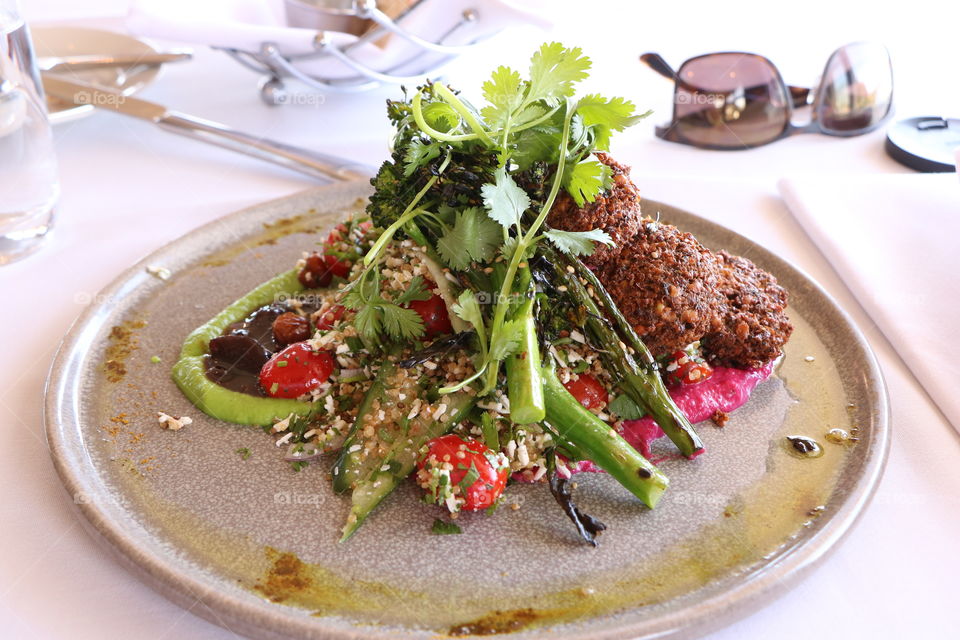 Healthy lunch- quinoa salad and falafel with cilantro on the top in a nicely plate arrangement 