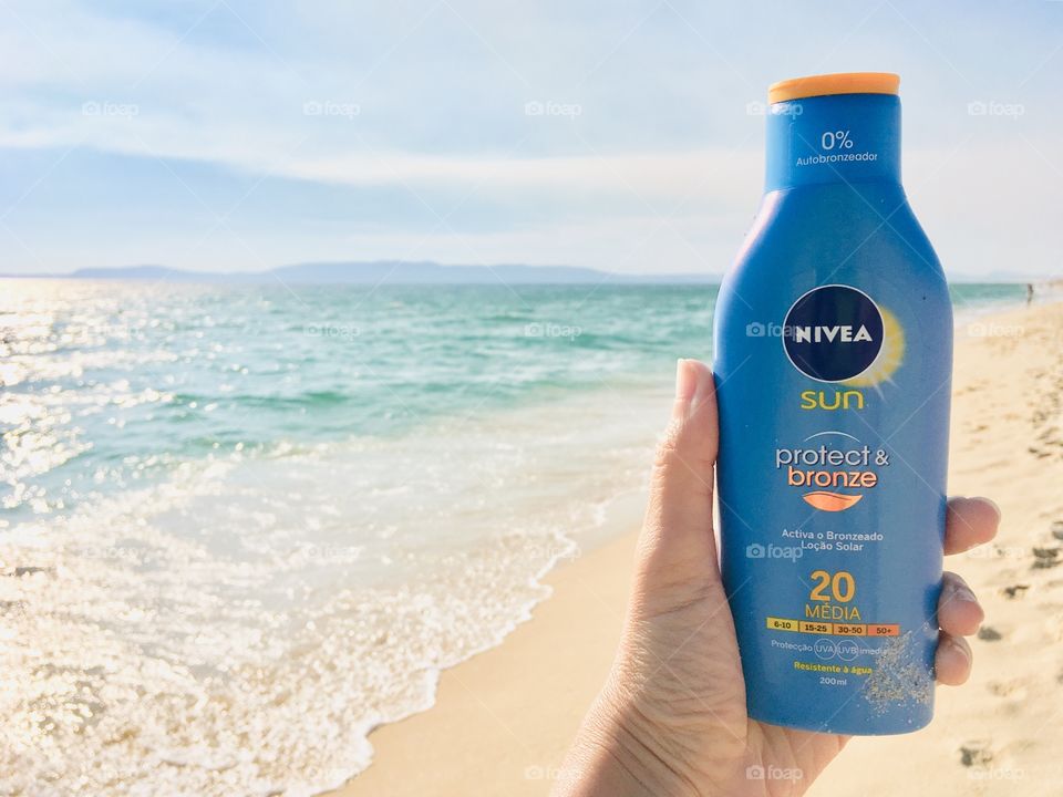 Nivea Sunscreen, Hand holding bottle of Nivea Sunscreen in the beach 