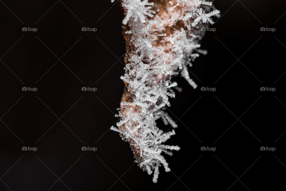 Beautiful icy crystals covering a small frozen piece of hanging metal