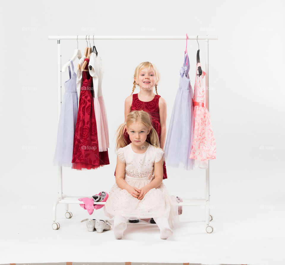 Two cute sisters is posing and playing with clothes and having fun.