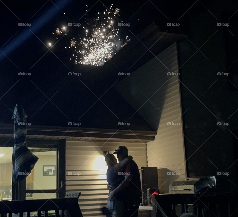 Couple hugging with firework in background 