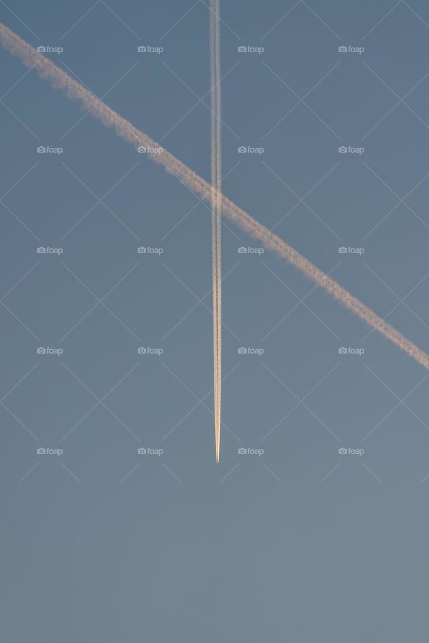 An airplane flying at dawn with a trail of engines