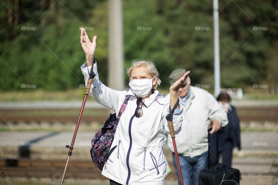 Senior woman with face mask and Nordic walking sticks