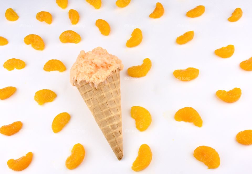 Orange sherbet on a waffle cone with with background and mandarin oranges flat lay set up 