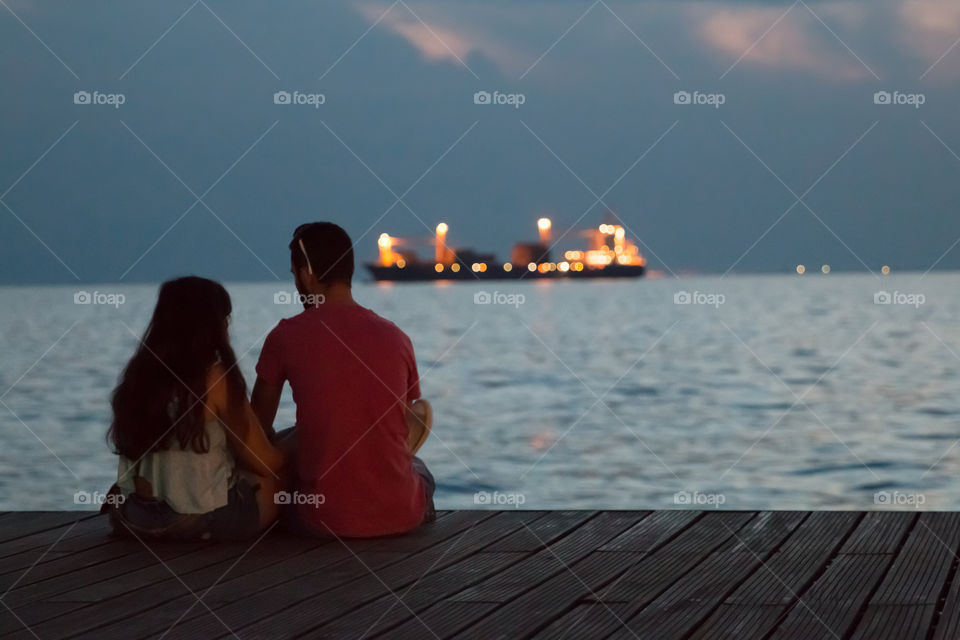 Couple In Love Sitting At The Dock Talking And Enjoying The Night View
