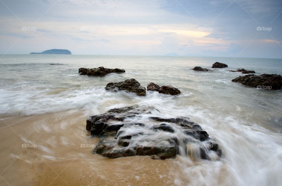 Sea waves lash line impact rock on the beach.