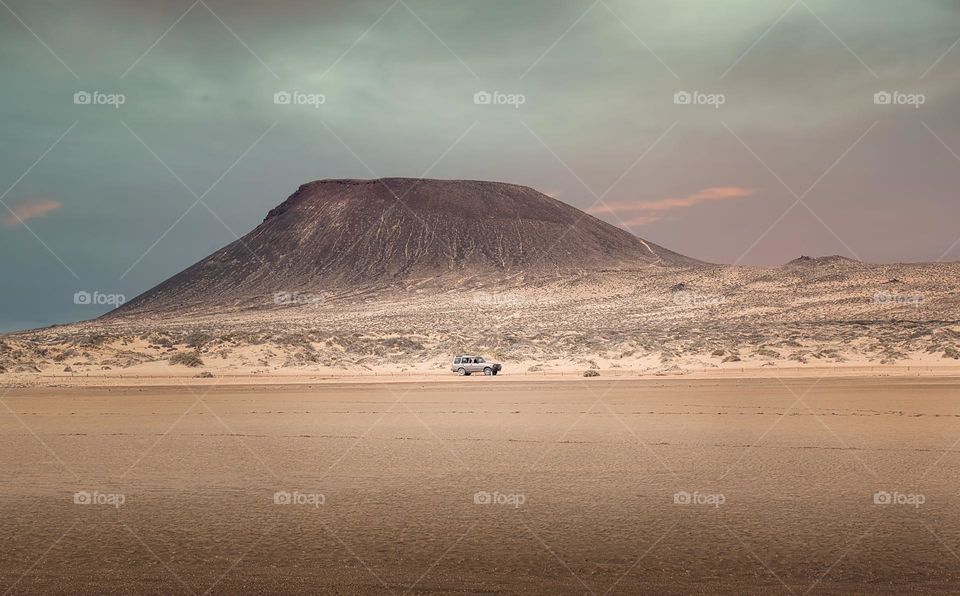 Jeep 4x4 driving trough sandy desert landscape under volcano at La Graciosa Island, Canary Islands