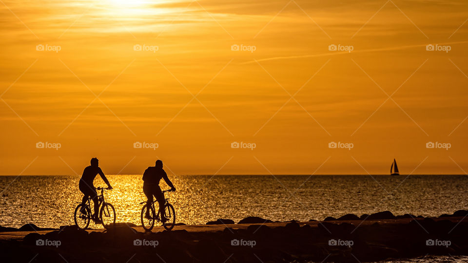 silhouette of people biking on the pier during the golden hour of sunset