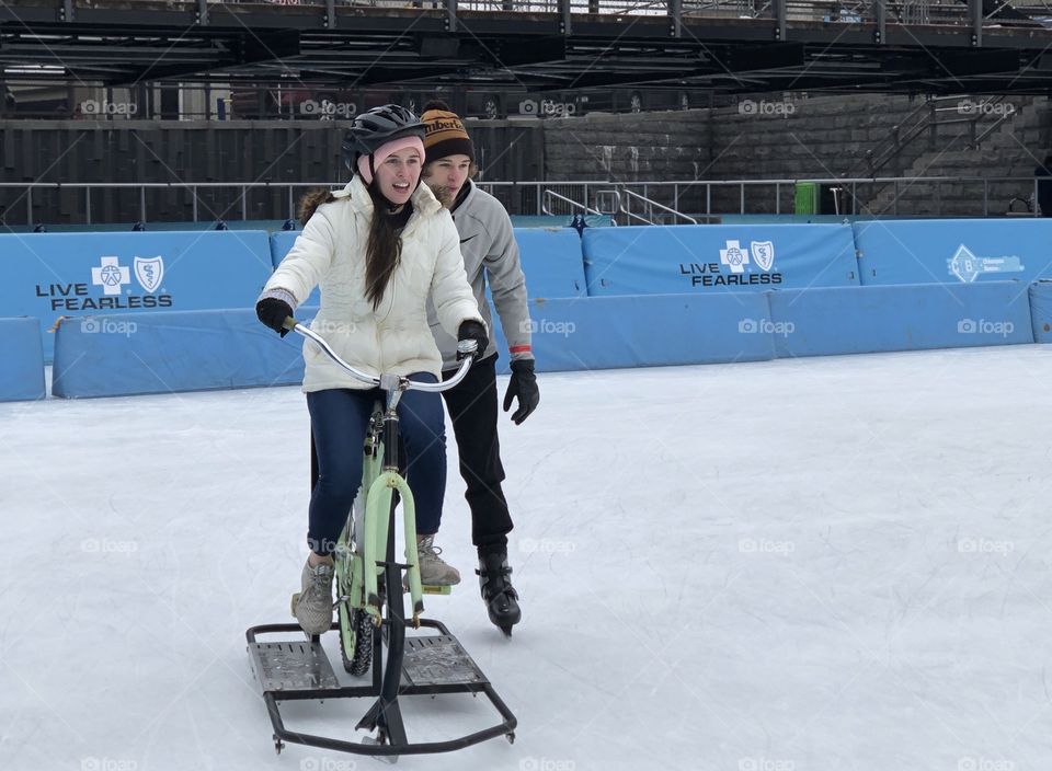 Friends having fun in the winter, ice bikes and ice skating at the rink outdoors