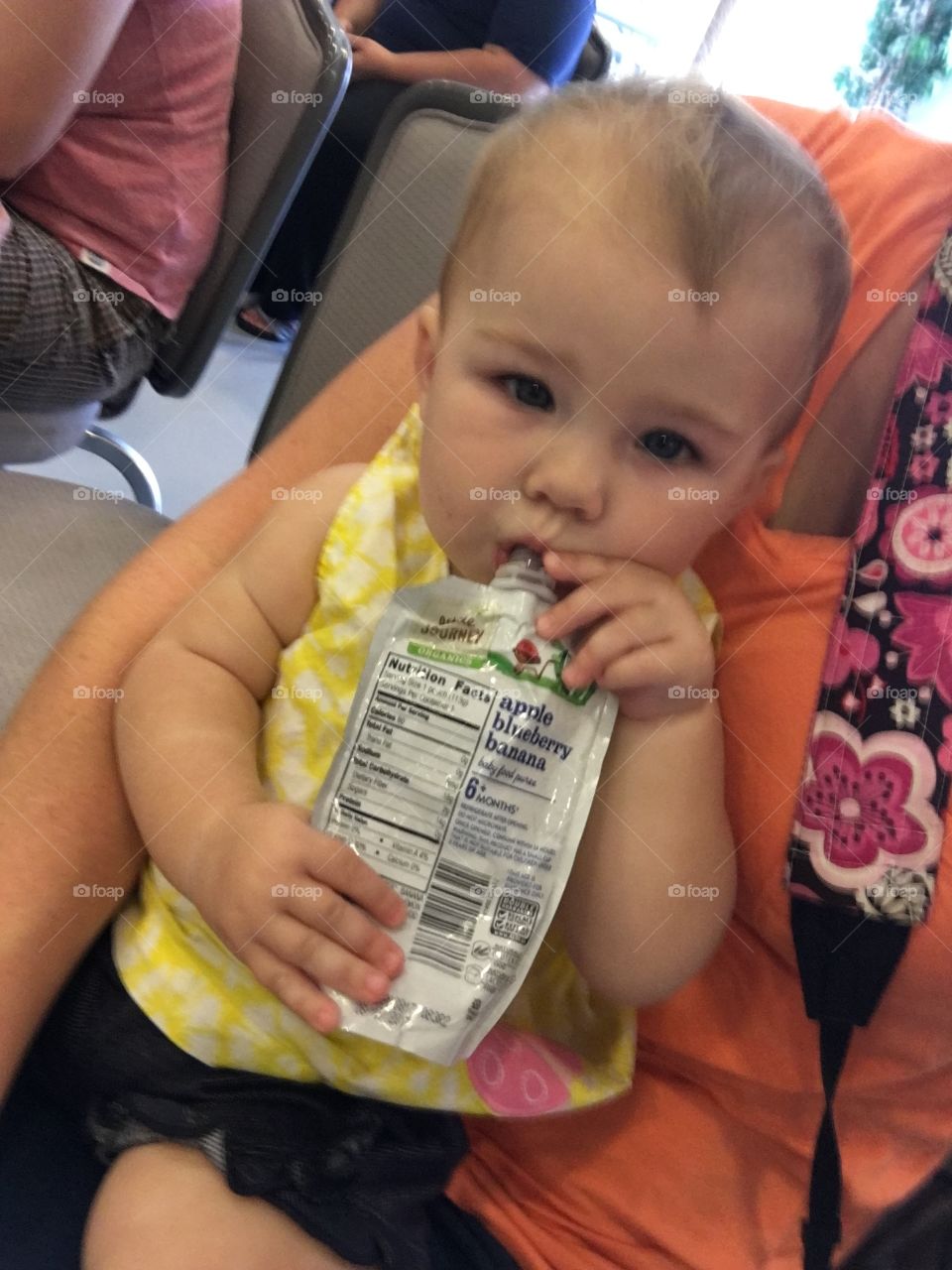 Baby girl on mother's lap with baby food