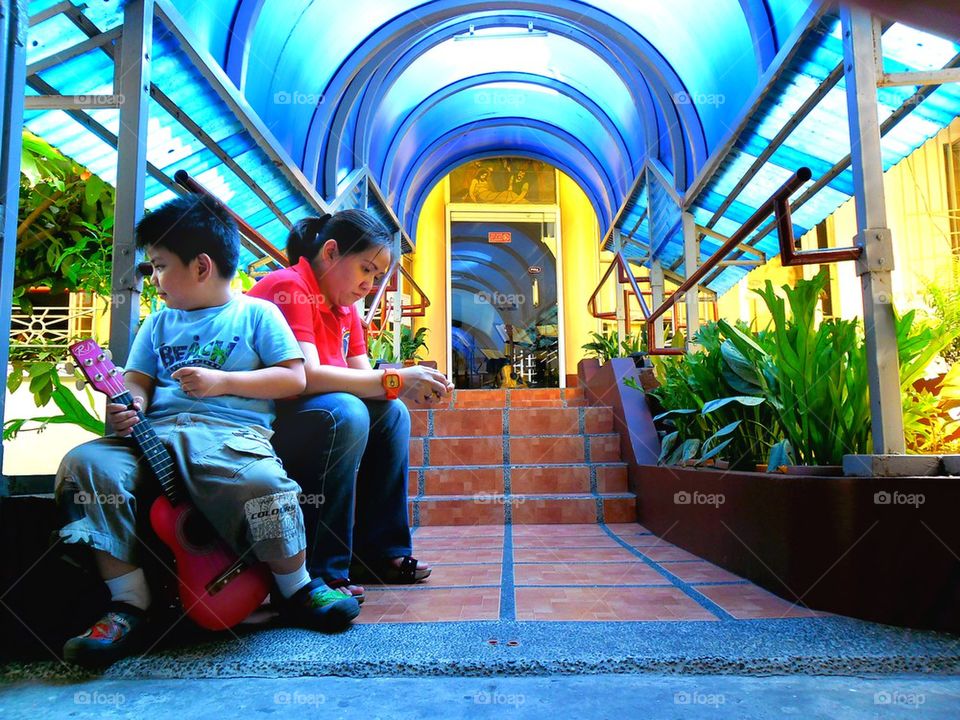 asian woman and child sitting at a covered part of a park