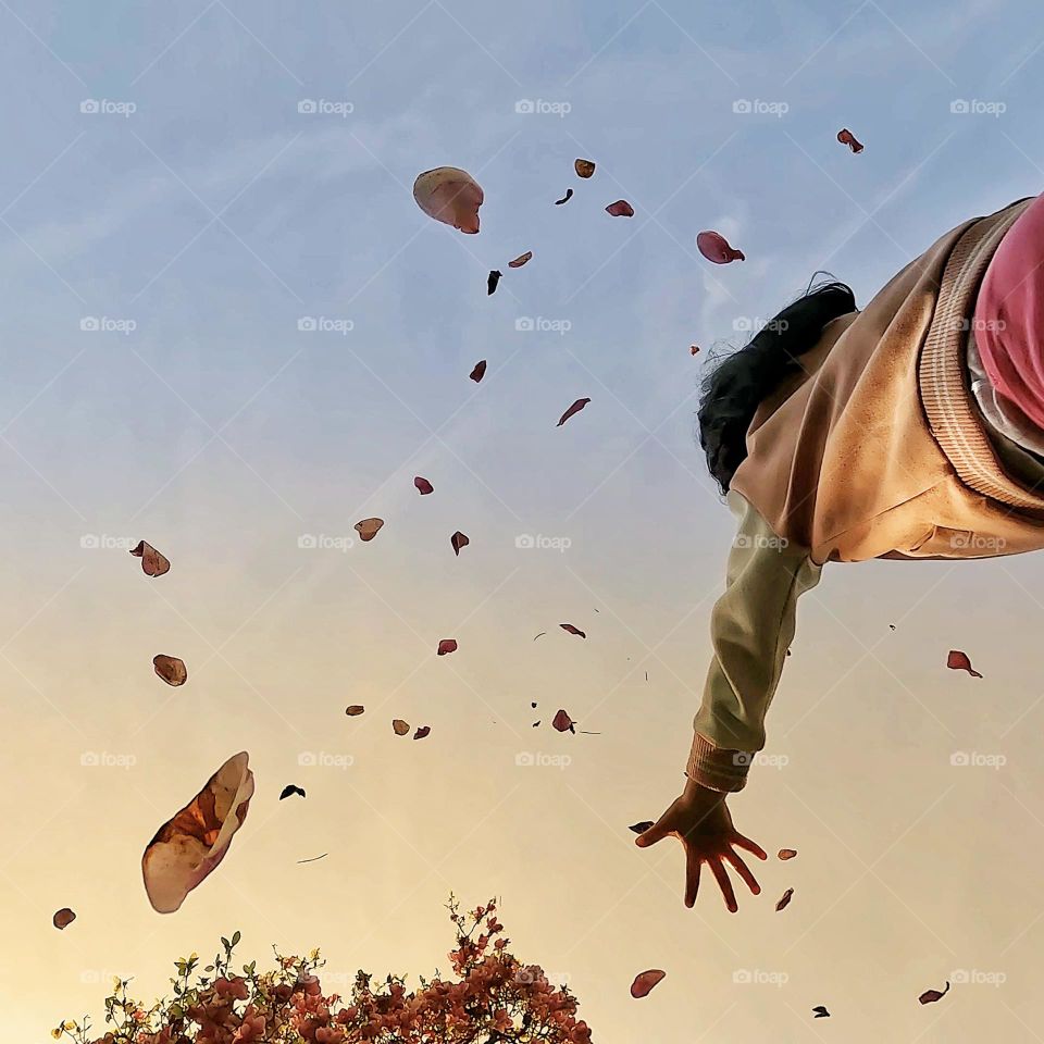 Child playing under falling leaves