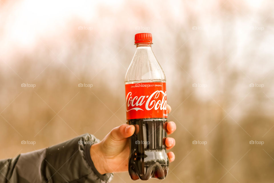 Hand holding a bottle of coca cola