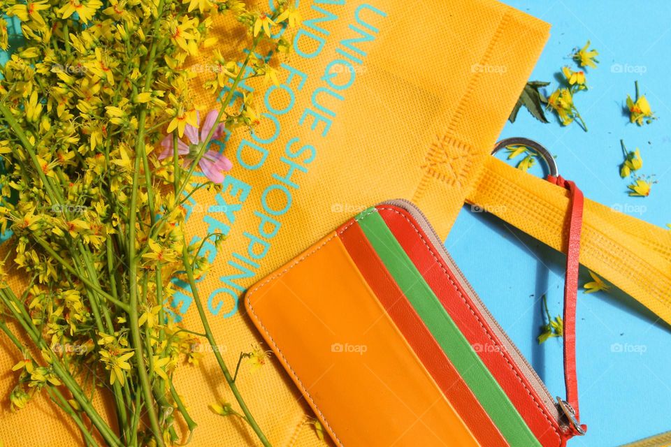 Market bag, wallet and yellow flowers on a blue background.  Dominance of rainbow colors. Pride colors