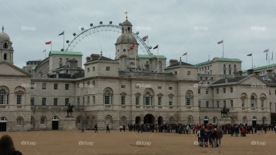 A view of London’s eye from the back of the parliamentary buildings as people gather to witness the changing of the guard on a normal cloudy British day.
