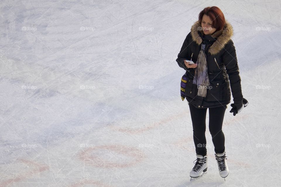 Woman on ice rink holding up cellphone