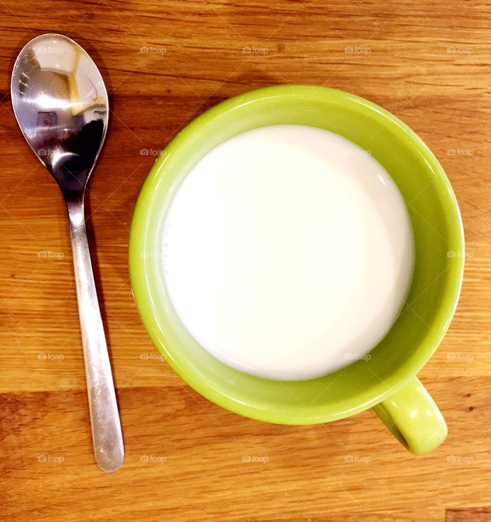 High angle view of milk, with spoon on wooden