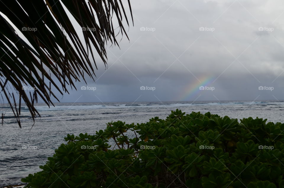 storm clouds, rain and rainbow over ocean