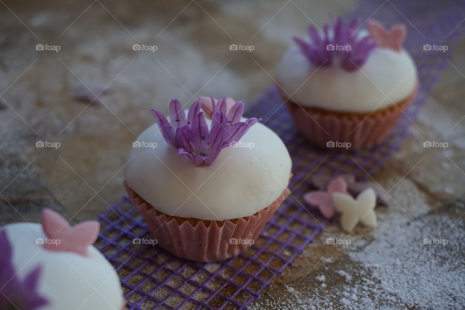 Iced fairy cakes with edible flower decorations 