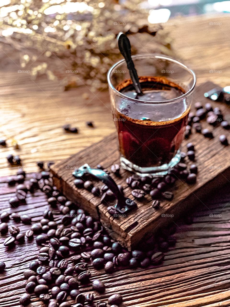 A cup of coffee and some coffee bean on the board and table top