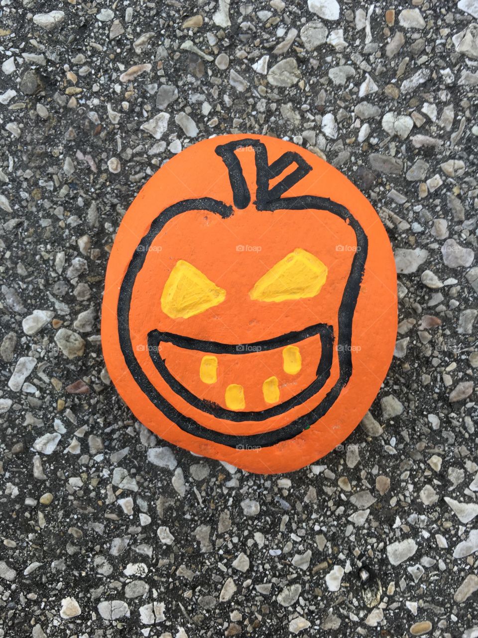 Halloween time with a comceptual pumpkin carved and painted on a stone