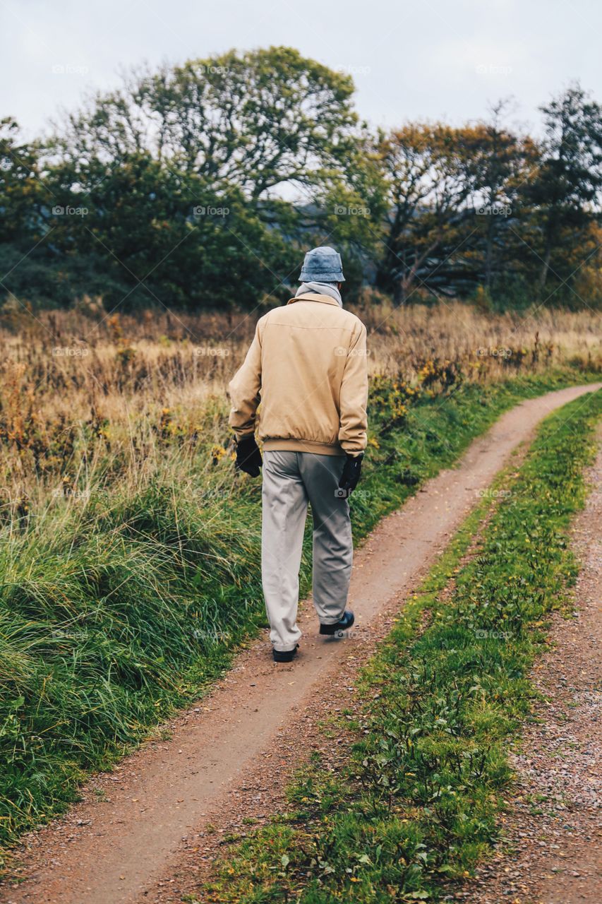 Elderly man walking on a country road 