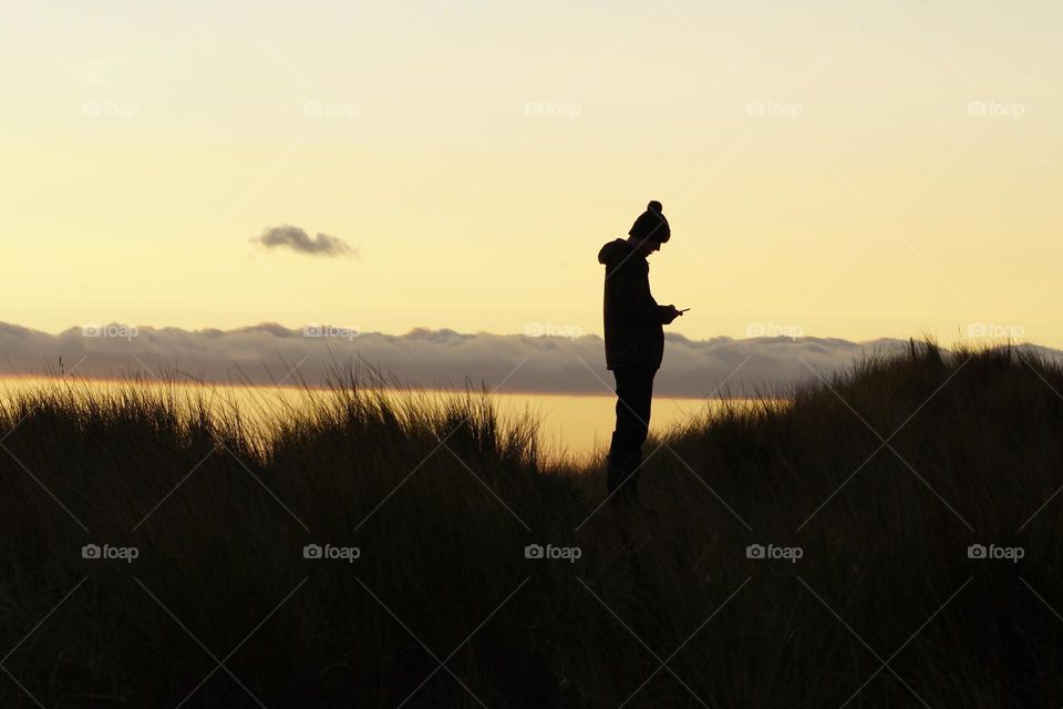 Daytripper … a visit to Lindisfarne/Holy Island on a beautiful blue sky day in January … love this shot of my son using his phone …  taken at sunset with the unusual clouds loitering in the background 