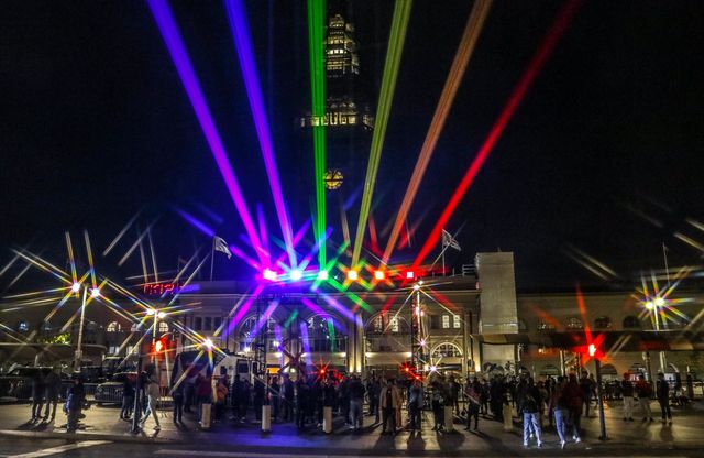 San Francisco Pride 2023 laser light display of the pride flag colors illuminating the sky in front of the Ferry Building on the Embarcadero as people gather to celebrate 