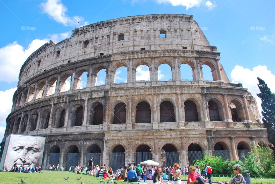 Colosseum . Tourists gather outside the Roman Colosseum under s bright blue summer sky 